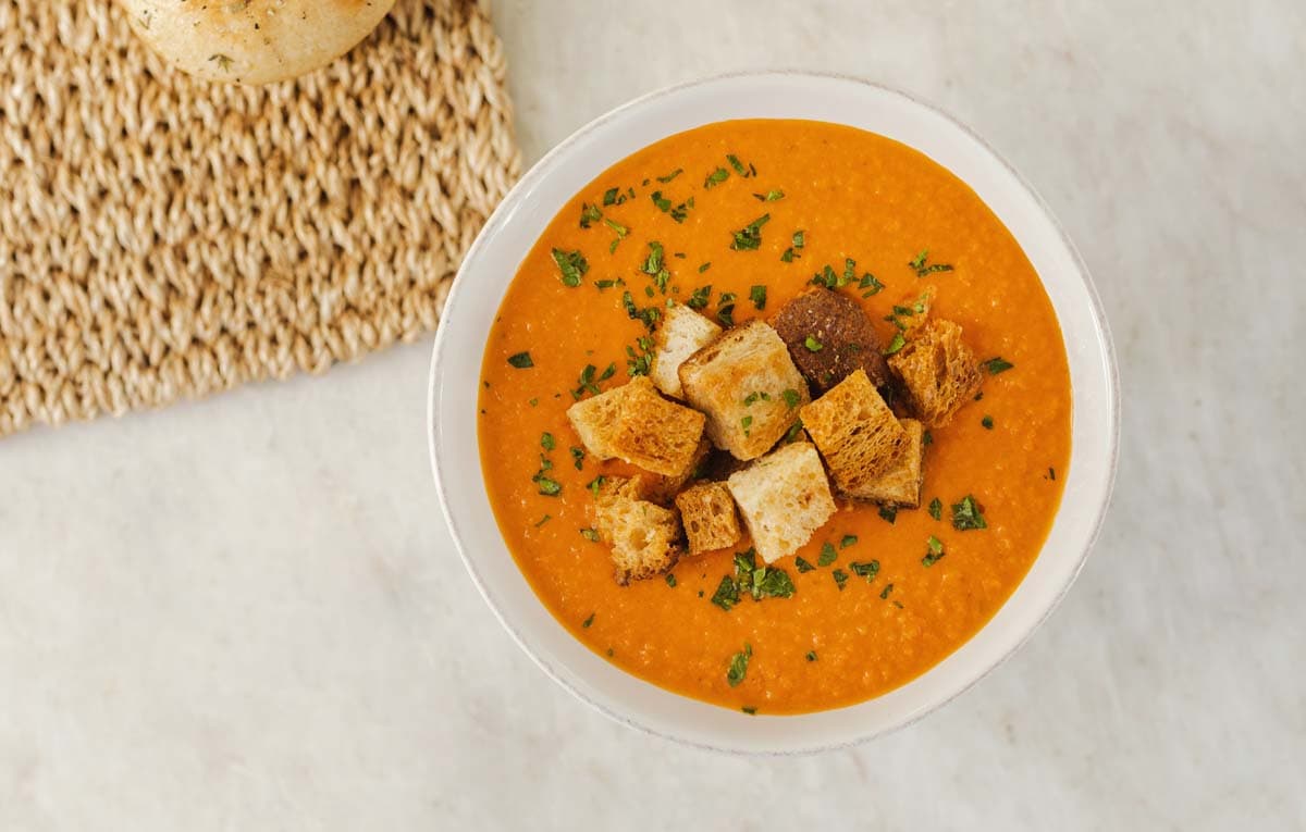 Bowl of tomato soup garnished with basil and croutons