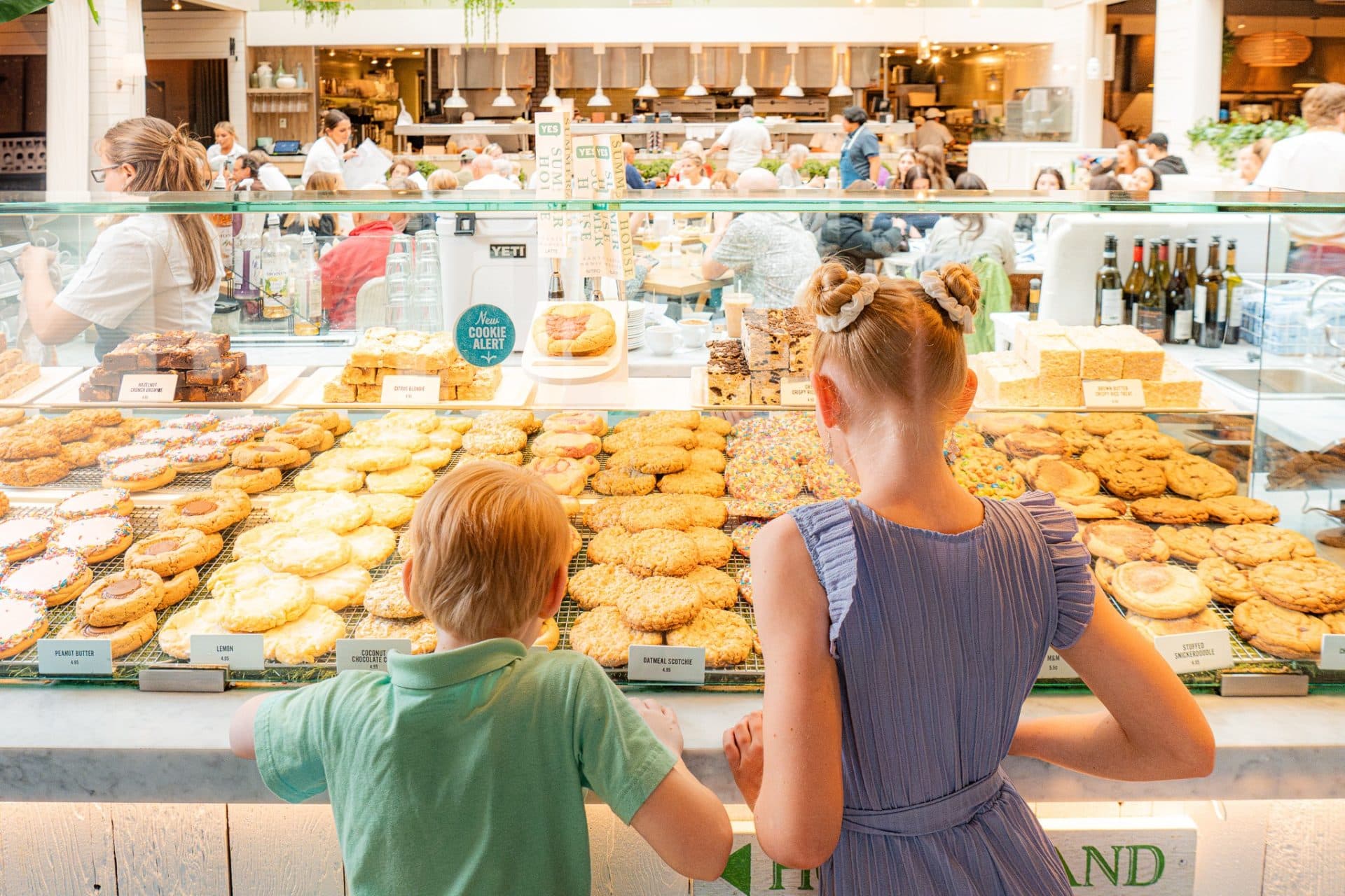 two kids with their back to the camera standing in front of a display of cookies